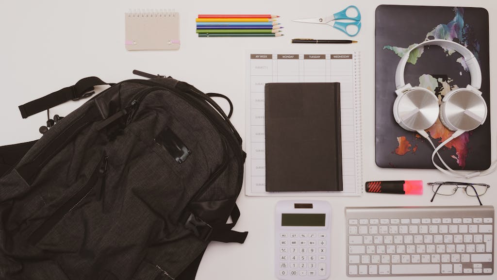 Top view of a clean desk with office supplies, tech gadgets, and stationery for efficient work.