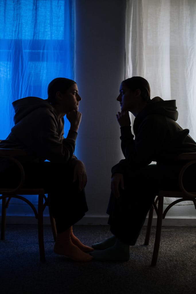 Two silhouetted figures facing each other evoke themes of introspection and duality.