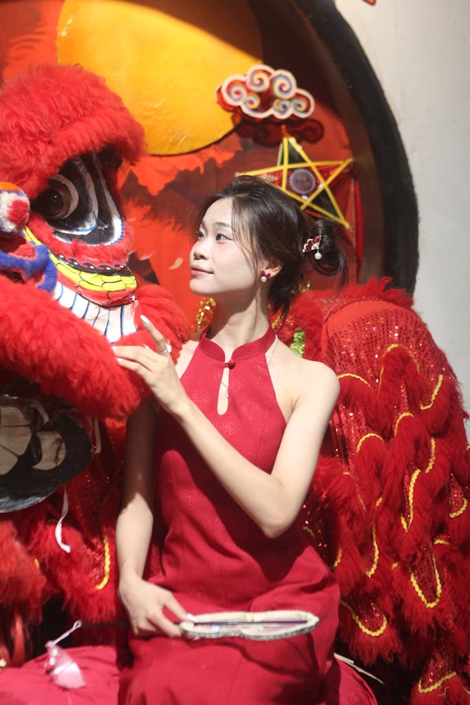 Asian woman in red dress with traditional dragon costume for Lunar New Year celebration.