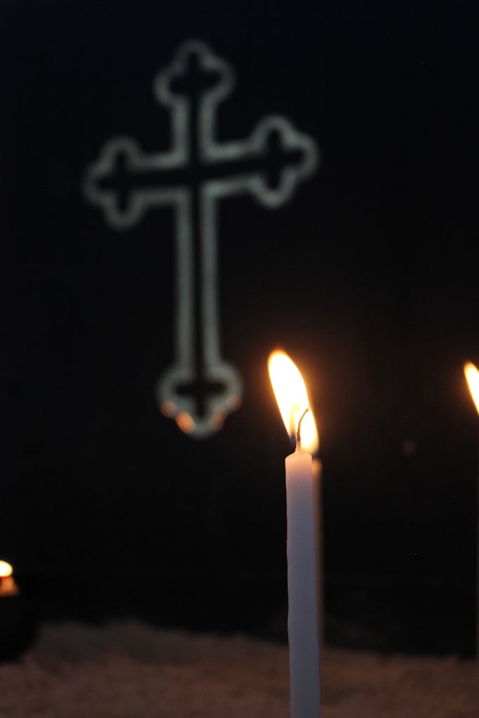 A lit candle with a cross in the background, symbolizing faith and spirituality.